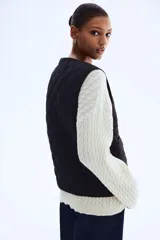 Chaleco de tejido guateado con diseño acolchado en forma de rombos, cuello redondo, cierre frontal con botones a presión y dos bolsillos delanteros de parche.