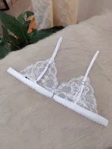 Conjunto de lencería compuesto por un bralette triangular de encaje floral con breteles regulables y una bombacha tipo tanga a juego con detalles de encaje y tiras ajustables.