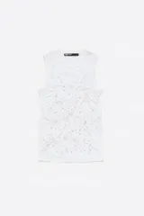 Top blanco de algodón con corte ajustado, escote redondo y manga sisa. Decorado con piedras fantasía en el frente.