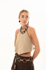 Top de gamuza color visón con escote halter y costuras decorativas con detalle de tientos de cuero en los bordes laterales.