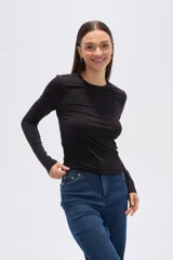 Remera verde esmeralda de manga larga, corte ajustado y cuello redondo.