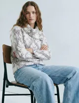 Buzo de tejido de punto con cuello vuelto que se ajusta con botones. Presenta un diseño jacquard en tonos blanco, gris y rosado pálido.