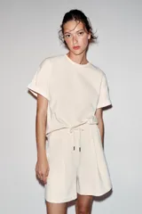 Camiseta de corte regular fit y color blanco, con cuello redondo, mangas cortas con vuelta y bajo recto.
