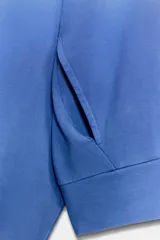 Chaqueta azul de algodón con cuello alto, cierre frontal de cremallera, bolsillos laterales y mangas largas con puños elásticos.