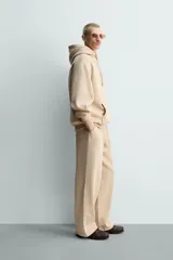 Pantalón jogger de corte relajado y pernera ancha, confeccionado en tejido de algodón con interior perchado. Presenta cintura elástica con cordón interior, bolsillos laterales y un bolsillo trasero de plastrón.