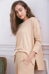 Remerón de tela acanalada color beige, con corte holgado, mangas tres cuartos y aberturas laterales en el ruedo.