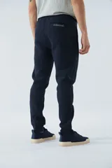 Pantalón de felpa gris para hombre con logo estampado y en goma, bolsillos con cierre, cierres en los tobillos, cintura ajustable y puños.