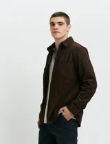 Sobrecamisa de pana color marrón, con manga larga, cierre frontal con botones y dos bolsillos frontales con solapa y botón.