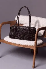 Cartera tipo baguette color marrón con textura efecto animal print, formato alargado, doble asa larga para el hombro y cierre superior.