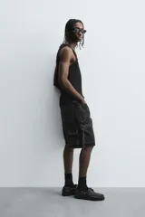 Bermuda de corte relajado en denim de algodón color beige, estilo cargo, con cinco bolsillos y bolsillos plastrón con solapa en las perneras.