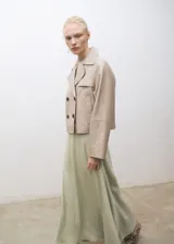 Abrigo corto tipo chaqueta de cuero ovino color beige, con diseño de doble botonadura, solapas con muesca y manga larga.