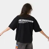 Remera de algodón con corte boxy, color negro, con estampa gráfica en blanco en la parte posterior que incluye el logo de la marca y texto descriptivo.