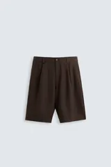 Bermuda de corte regular fit, color marrón oscuro, confeccionada en tejido con lino. Presenta pliegues frontales, bolsillos delanteros y bolsillos traseros de vivo. Cierre frontal con cremallera y botón.