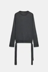 Jersey de punto liso color gris oscuro, con cuello redondo, manga larga y detalle de tiras largas en los laterales del ruedo.