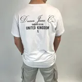 Remera blanca de algodón con estampado negro en el pecho con el texto "Duxon Jeans Co. Origin of Design United Kingdom" y una figura de ajedrez.