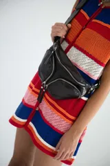 Riñonera negra de cuero vacuno con correa regulable, cierre superior con doble cremallera y bolsillo frontal con cremallera.