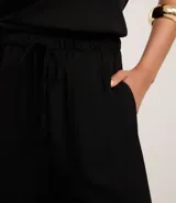 Pantalón femenino negro de tejido airflow, con corte recto, elástico y lazo en la cintura.