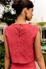 Top corto sin mangas color rosa fresa, con cuello redondo y diseño bordado con perforaciones en toda la prenda.