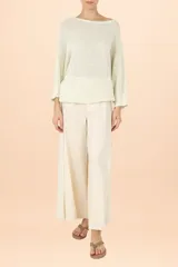 Suéter de punto color marfil con cuello barco, mangas estilo murciélago de largo tres cuartos y corte holgado. Presenta un tejido con sutiles destellos brillantes.