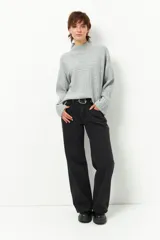 Polera gris de tejido tramado, cuello alto y mangas holgadas.