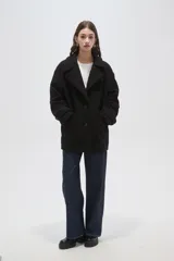 Tapado de lana color negro, con cuello de solapa, cierre frontal de botones y bolsillos laterales.