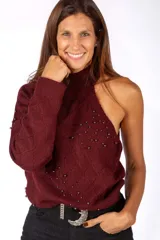 Sweater de punto negro con diseño asimétrico de un solo hombro y cuello alto. Presenta un patrón de rombos en relieve y está decorado con pequeñas tachas metálicas distribuidas por toda la prenda.