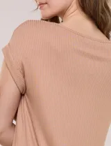 Remera blanca de punto acanalado con escote redondo adornado con tachas metálicas en el cuello y hombros, mangas cortas japonesas y ruedo curvo.