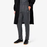 Pantalón de jogging negro con estampado de monogramas geométricos en gris y blanco. Tiene corte recto, cintura con cordón ajustable, bolsillos laterales y logo de cocodrilo bordado en el muslo.