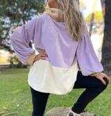 Polerón de corte holgado con mangas largas abullonadas, confeccionado en terciopelo negro con detalles en beige y blanco.