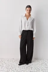 Pantalón wide leg de tiro medio y calce amplio, color marrón, con pinzas delanteras, cierre frontal y bolsillos laterales funcionales.