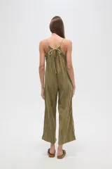 Mono de algodón color verde oliva, con textura plisada, escote en V y tirantes finos tipo lencero. Presenta bolsillos frontales y corte holgado.