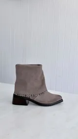Botas de cuero gamuzado color gris topo, con diseño versátil 2 en 1 que permite usarla en formato corto o largo. Presenta costuras decorativas en el contorno y taco cuadrado de madera oscura.