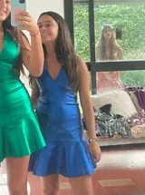 Vestido corto plateado de lentejuelas, con escote en V, breteles finos cruzados en la espalda y volados en el ruedo.