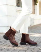 Botinetas de caña baja confeccionadas en cuero vacuno color chocolate, con paneles laterales en gamuza al tono. Presentan suela track de goma negra, cierre lateral interno y puntera redondeada.