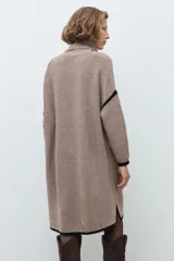 Vestido tejido de corte holgado y largo midi, con cuello volcado, mangas largas y detalles de ribetes en color negro en puños y ruedo.