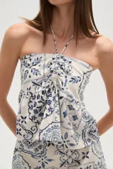 Top strapless de viscosa con estampado de azulejos en tonos azul y blanco. Presenta un diseño con cuello halter, detalle de fruncido central y un lazo decorativo en el frente.