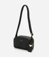 Cartera pequeña de hombro marca Satinato, confeccionada en PU con textura granulada. Presenta doble compartimento con cierre de cremallera metálica dorada, correa larga ajustable y un dije decorativo metálico con el logo de la marca.