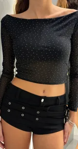 Short negro de tiro bajo confeccionado en material engomado, con diseño de doble cinturón integrado con ojales metálicos y hebillas laterales.