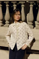 Camisa color crema con estampado de círculos marrones, cuello con volados y puntilla, y cierre frontal con botones.