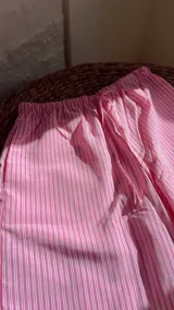 Pantalón de pijama largo rosado con rayas verticales blancas, cintura elástica y corte holgado.