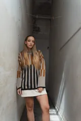 Sweater tejido a rayas horizontales color beige, marrón y negro, de cuello alto y corte holgado.