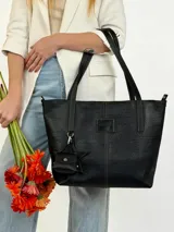 Cartera tote de cuero genuino color negro, con costuras visibles a contratono, asas dobles para hombro, parche frontal con logo grabado y charms colgantes en forma de estrella y mini monedero.