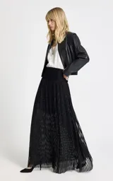 Pollera larga de tiro alto confeccionada en tejido de punto con acabado brillante de lurex. Presenta una cintura ancha estructurada, diseño con sutil transparencia y forro interior, con cierre de cremallera invisible en la espalda.