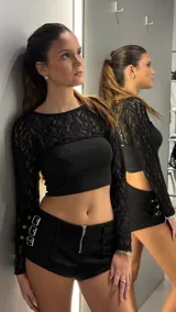 Top de encaje negro con mangas largas y diseño tipo bolero, que deja los hombros y la espalda descubiertos.
