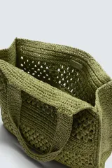 Bolso tipo shopper de diseño trenzado en color tostado, con estructura rectangular, dos asas de mano y compartimento principal abierto.