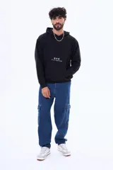 Buzo tipo canguro de felpa color negro, con capucha y bolsillo frontal. Presenta un estampado pequeño en el centro del pecho con tres estrellas y la frase 'art is for hyped people'.