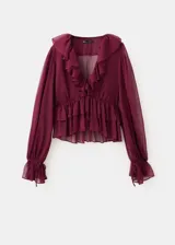 Blusa bordó de tejido fluido y semi transparente, con escote en V pronunciado, mangas largas abullonadas con volantes en los puños y detalles de volantes en el cuello y el ruedo.