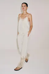 Pantalón de tiro medio con cintura elástica ajustable mediante cordones. Presenta un diseño fluido con bolsillos laterales ocultos y bajo decorado con una aplicación de encaje a contraste.