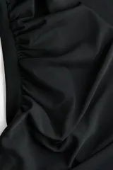 Top de manga larga de punto elástico color negro, con escote bote, detalles fruncidos en el busto y lateral, y una tira ancha colgante en la cintura.