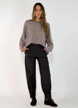 Pantalón de gabardina negro, de corte recto y holgado, con bolsillos delanteros y puños ajustados en los tobillos.